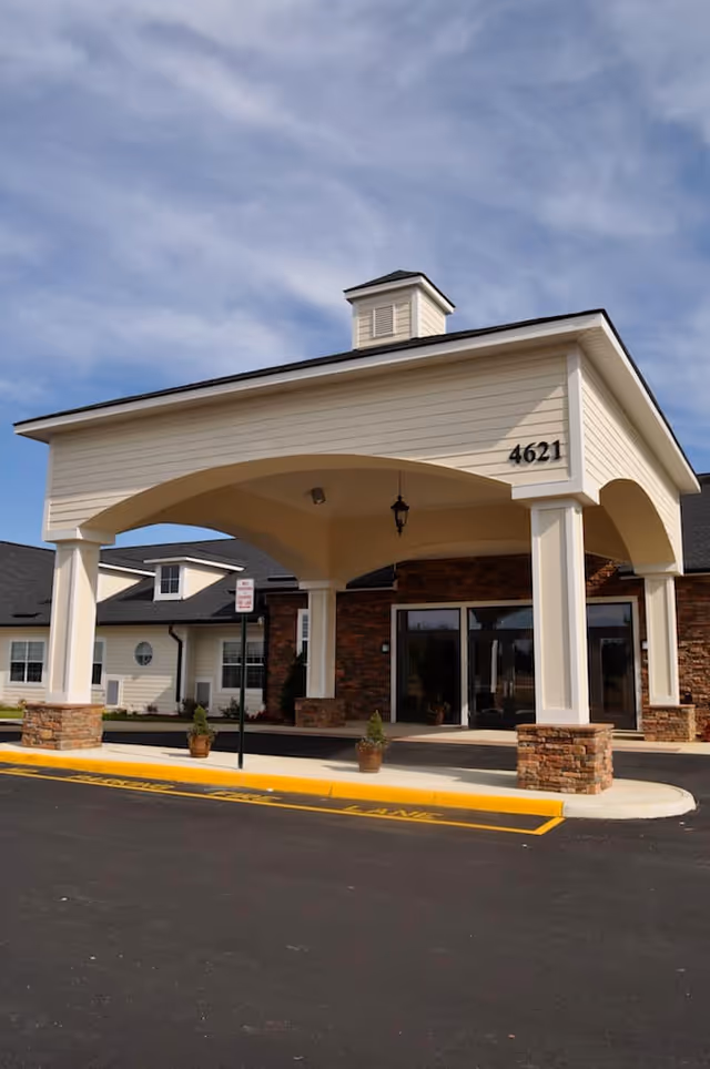 Entrance of Morningside House of Spotsylvania featuring a covered drop-off area with white pillars and stone bases, a building number 4621 displayed on the structure, and a clear sky in the background.