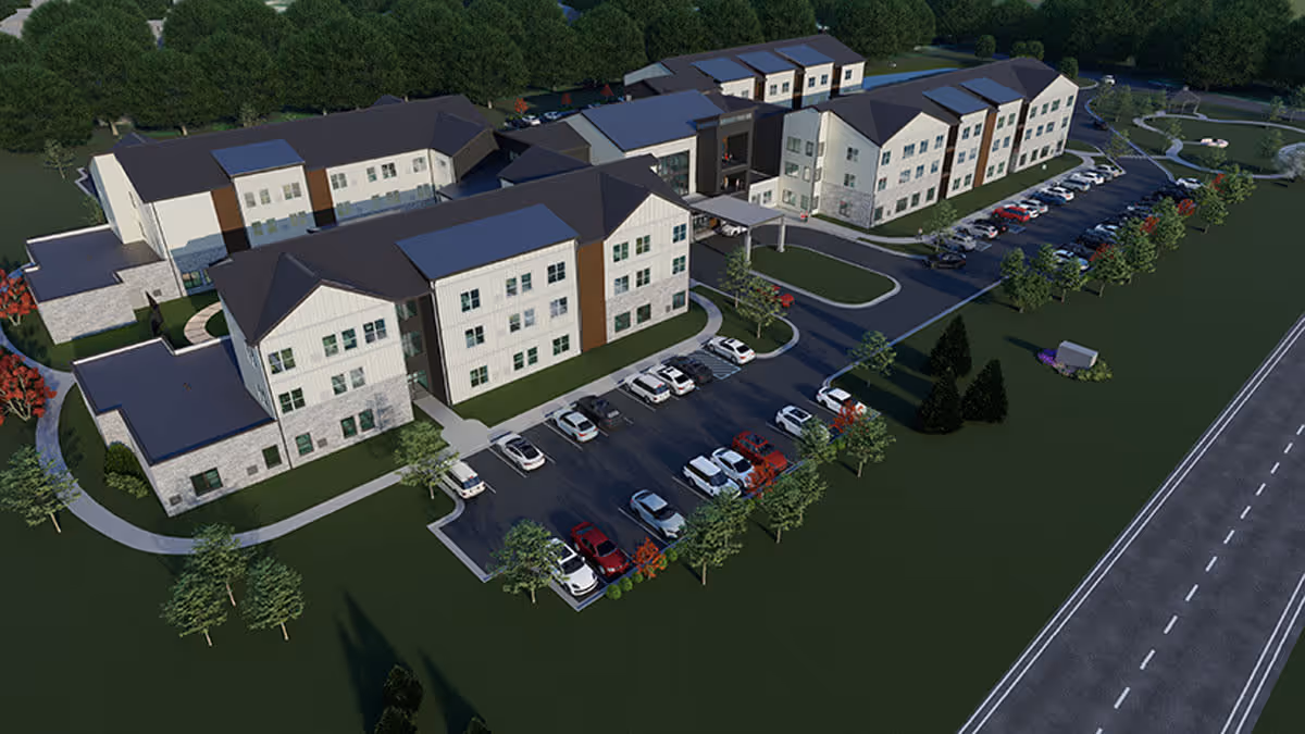 Aerial view of a large senior living facility named Astral at Franklin, showing multiple connected buildings with parking lots, surrounded by trees and green lawns, adjacent to a road.