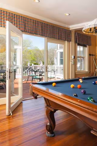Indoor recreation room with a pool table and glass doors opening to an outdoor patio.