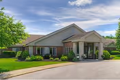 Front view of a single-story brick nursing home with landscaping.