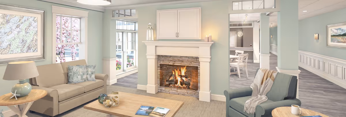 Sunlit communal living room featuring a sofa, armchair, coffee table and a lit fireplace with pastel walls and large windows.