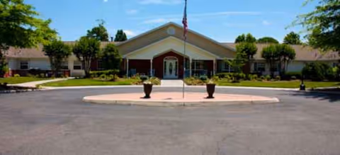 Exterior view of Brookdale Roanoke's front entrance with a circular driveway and flagpole.