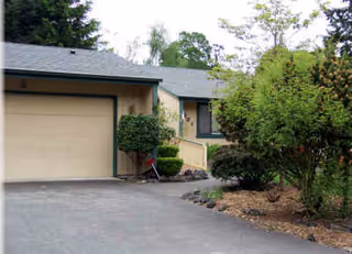 Exterior view of a single-story Bethel Home with driveway, garage, and landscaped shrubs.