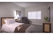 A neatly made bedroom with a bed, nightstand, lamp, armchair, window blinds, and dresser.