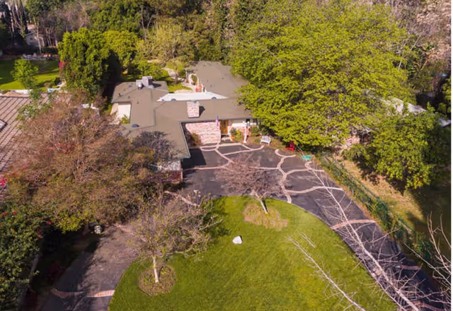 Aerial view of Jackie's Hideaway I exterior with trees, curved driveway, and green lawn.