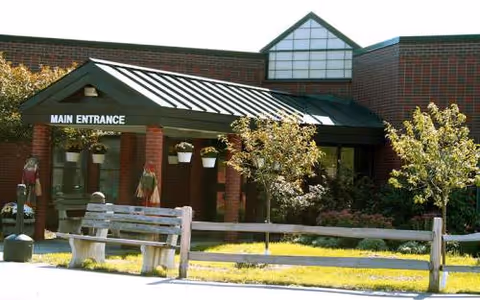Front entrance of Maine Veterans' Home Bangor, brick exterior, awning, benches, planters.