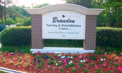 Outdoor brick sign for Brandon Nursing & Rehabilitation Center surrounded by colorful flower beds.