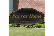 Wooden sign reading "Farrar Home Established 1900" in front of a brick building and lawn.