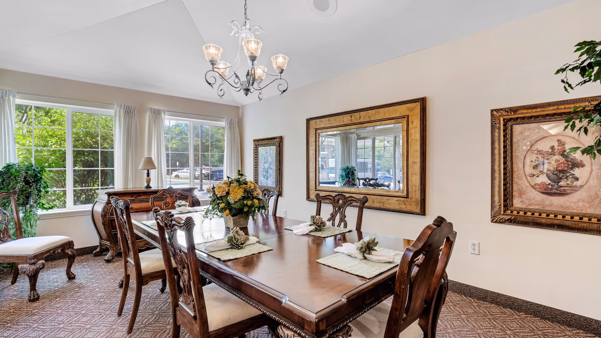 Formal dining room featuring a large wooden table and chairs under a chandelier, with windows, a mirror, and framed artwork.