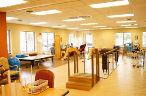Bright rehabilitation gym in a senior facility with parallel bars and exercise equipment.