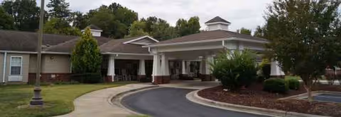 Exterior view of a senior living facility with a covered entrance and curved driveway.