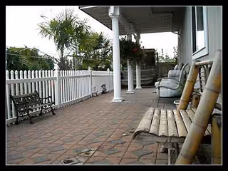 Outdoor patio of a senior living facility with benches, chairs, and a white picket fence.