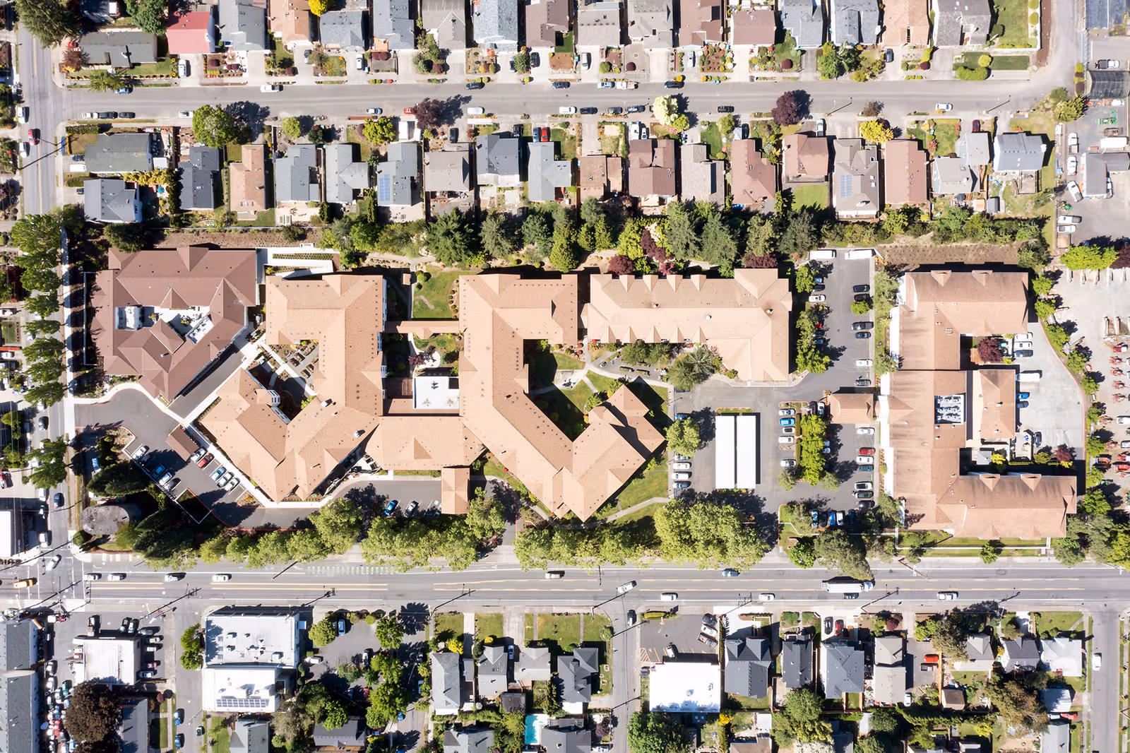 Aerial view of a large senior living campus with multiple connected buildings, parking areas, lawns, and surrounding residential streets.