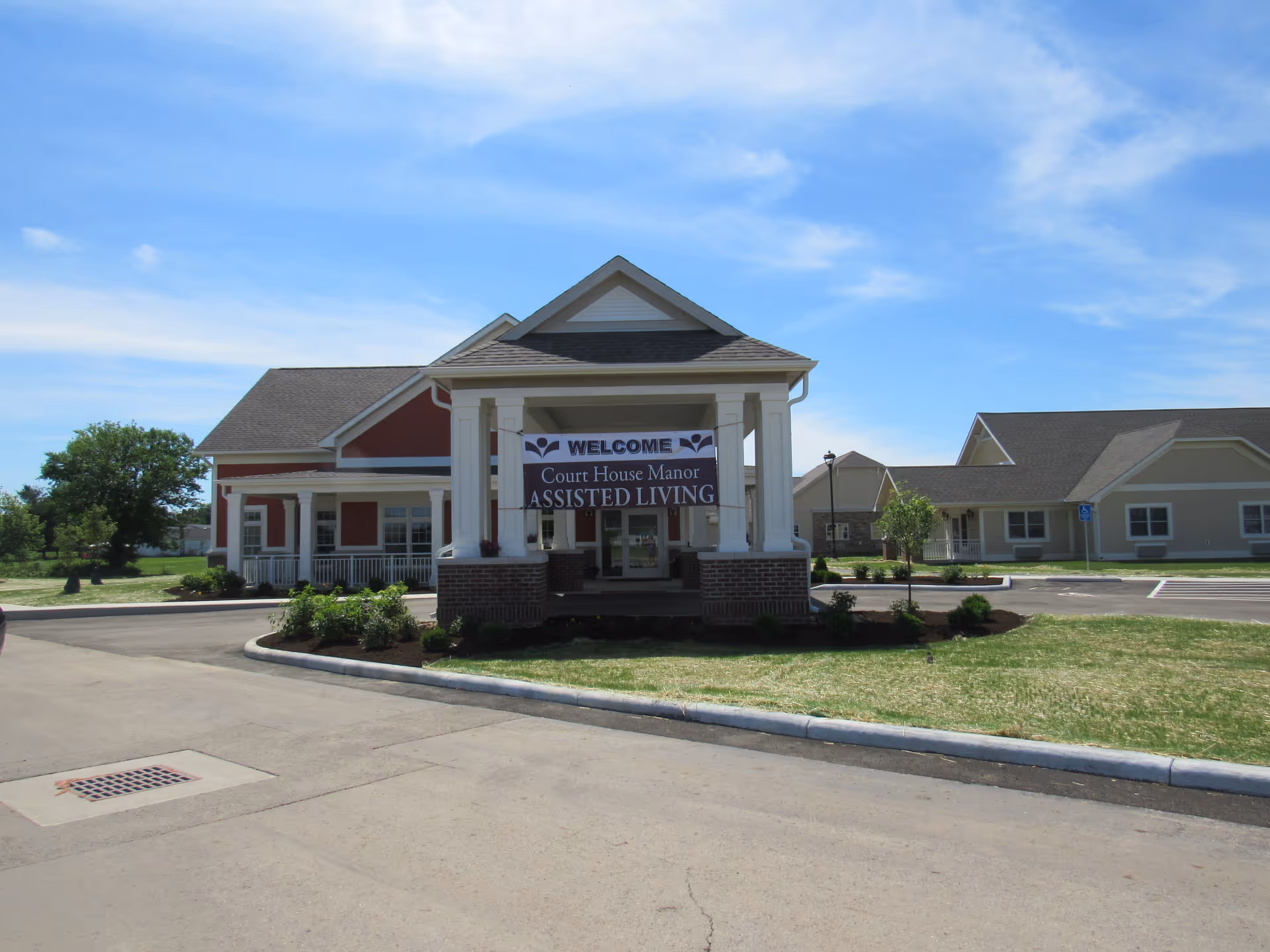 Front entrance of Court House Manor assisted living facility with a covered portico and a welcome sign.