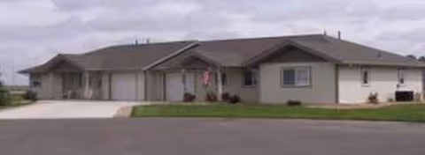 A single-story senior living center with a front driveway and manicured lawn.