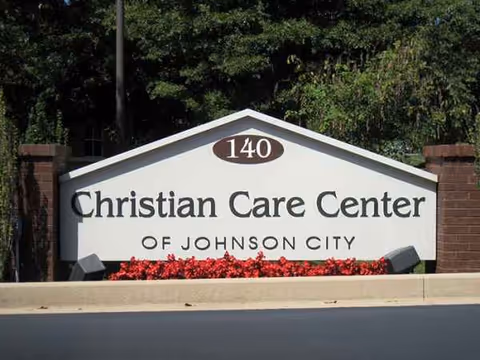 Exterior sign for Christian Care Center of Johnson City with red flowers beneath