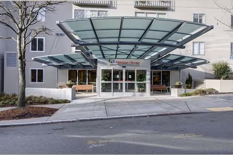 Front entrance of Horizon House with a glass canopy and benches outside.