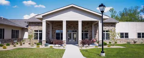 Front view of Woodland Country Manor with a stone entry, columns, and a green lawn.