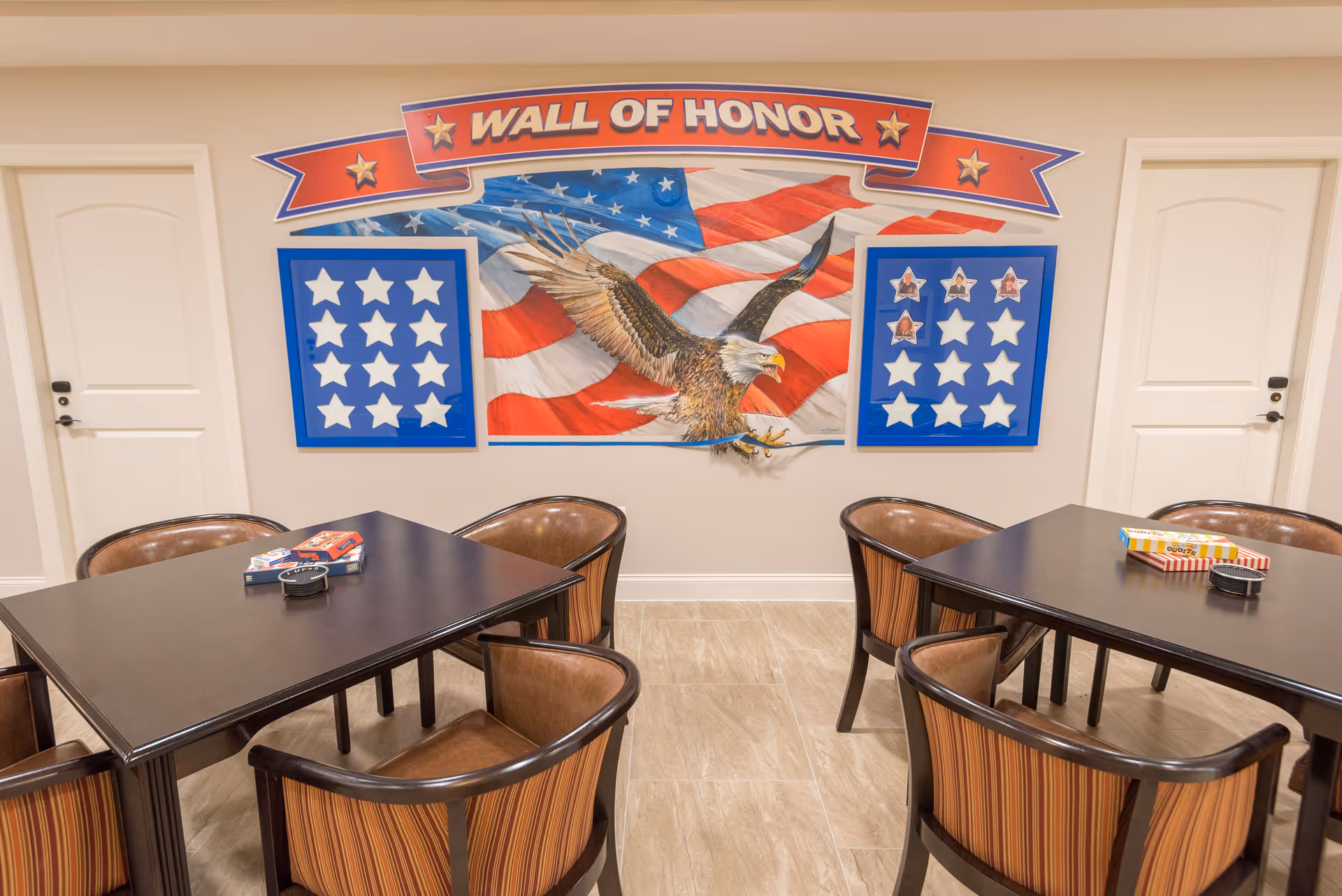 Indoor common room with tables and chairs and a large 'Wall of Honor' patriotic mural featuring an eagle and stars.