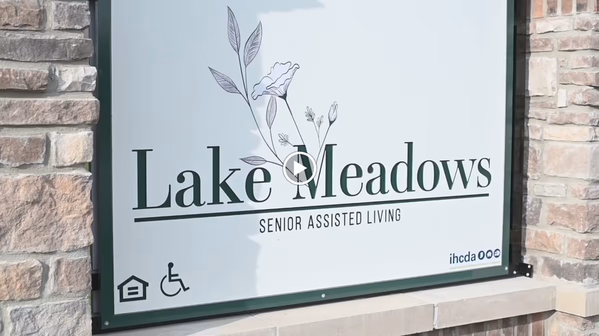 A large sign on a stone exterior reading "Lake Meadows Senior Assisted Living."