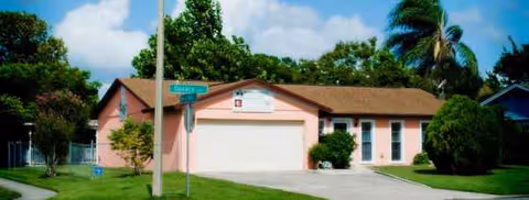 Pink single-story building with a two-car garage and manicured lawn.