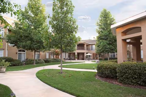 Exterior view of Quail Park on Cypress with trees, curved walkways, and a beige building.