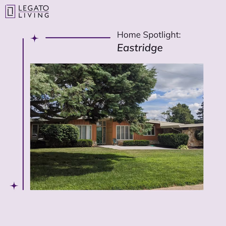 Exterior view of a single-story residential building named Eastridge, surrounded by green grass, bushes, and large trees under a partly cloudy sky.
