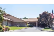 Exterior view of a senior care facility with entrance, driveway, and landscaping.