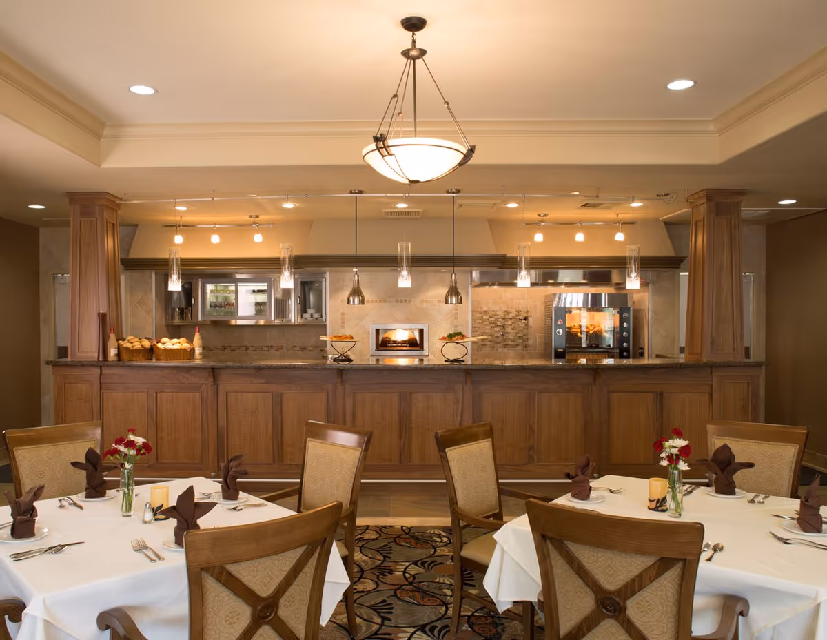 Elegant dining room with set tables and a wooden service counter/open kitchen in the background.