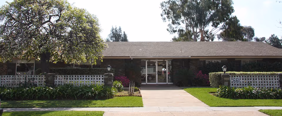 A single-story senior care center with a glass entrance and well-maintained landscaping.