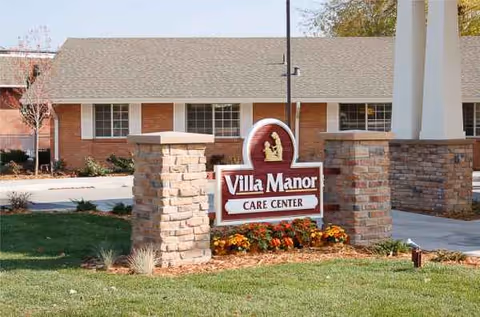 Exterior view of Villa Manor Care Center with a brick sign and landscaped front yard.