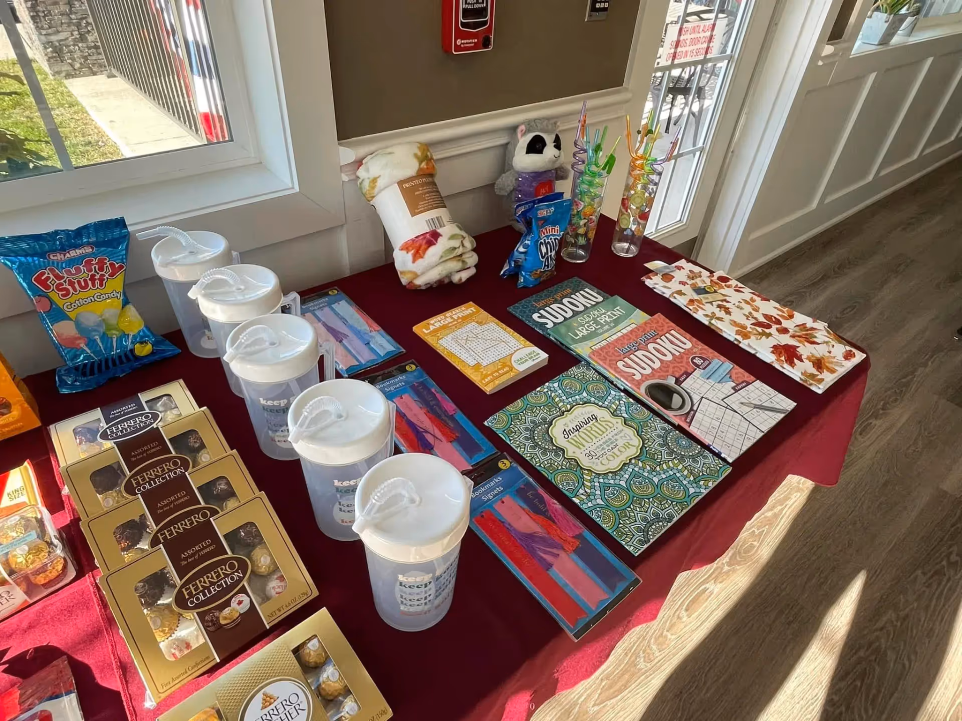 Lobby display table with brochures, snacks, and drinks near a windowed hallway.