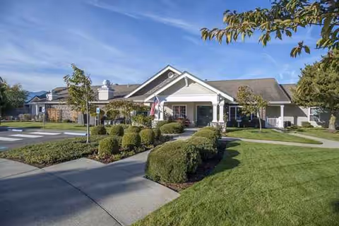 Front view of a single story senior living facility entrance with manicured lawn.