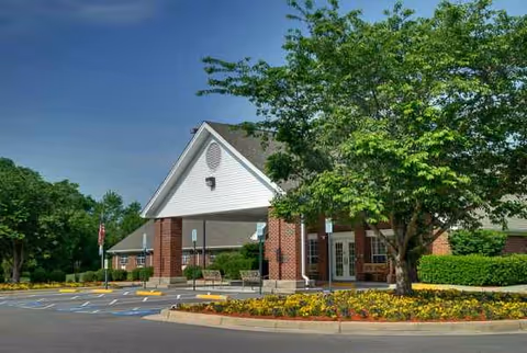 Exterior view of a senior living center entrance with brick columns and landscaping.