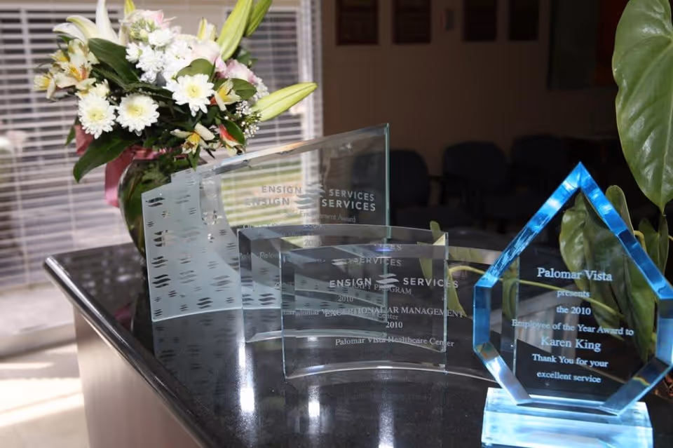 Glass awards and a vase of flowers displayed on a reception desk in a waiting area.