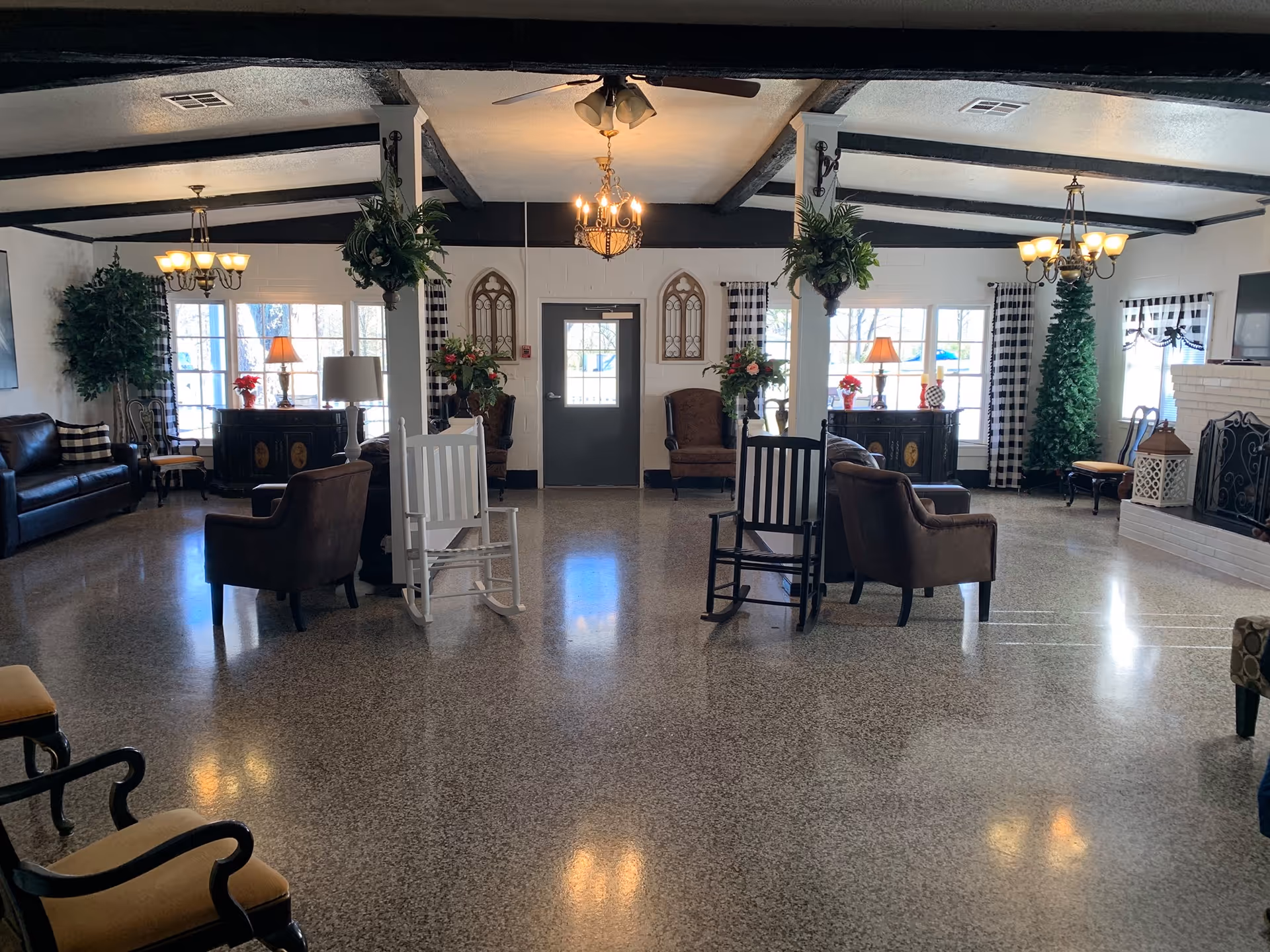 Bright, spacious common lounge with armchairs, rocking chairs, chandeliers, a fireplace and large windows.