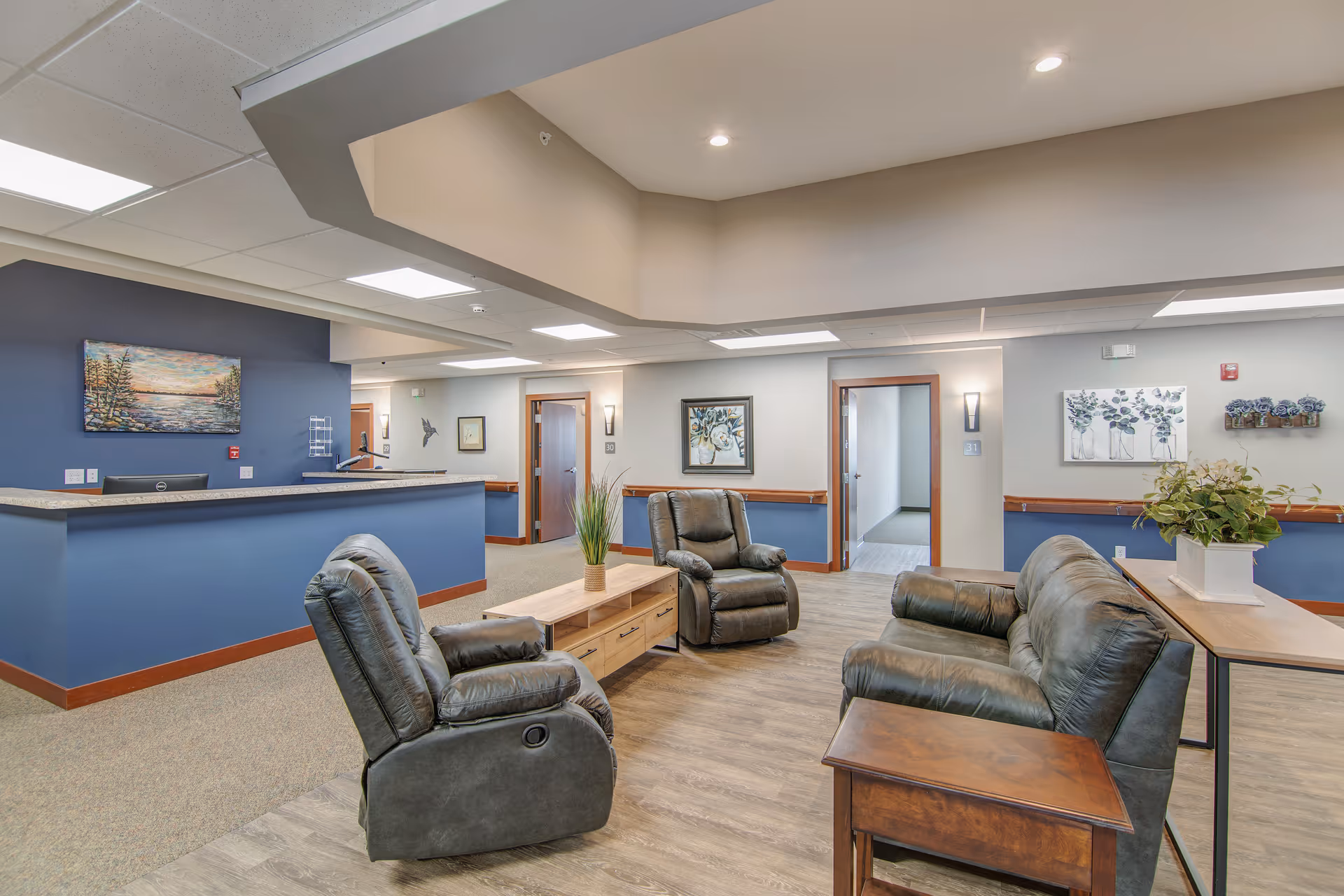 Reception lounge with leather recliners, a coffee table and a front desk in a senior living facility.