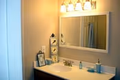 Bathroom vanity with sink, mirror, overhead light fixture, and decorative items on the countertop.