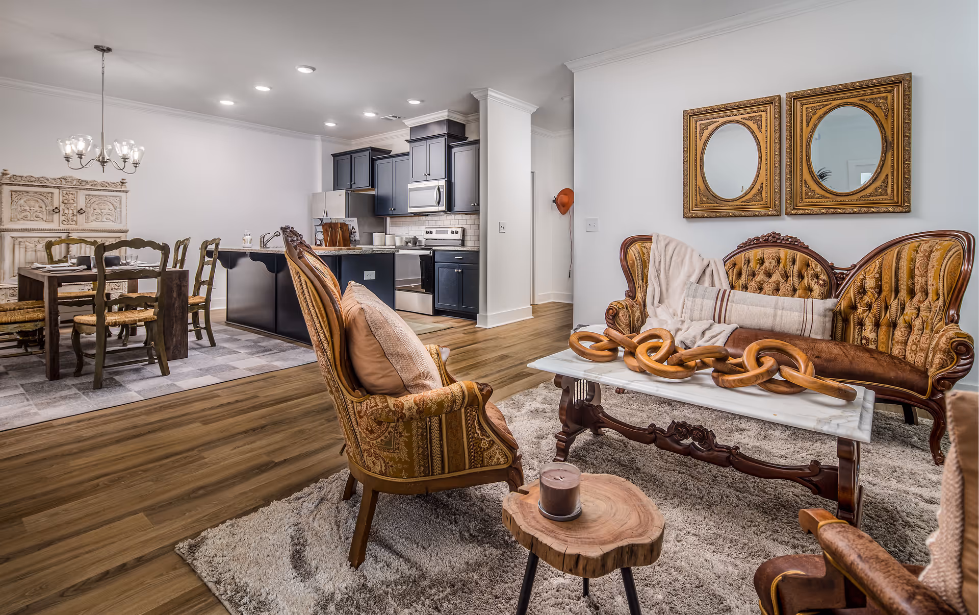 Open-plan living area with vintage upholstered seating around a coffee table, and a dining table and kitchen visible in the background.