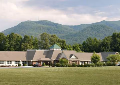 Exterior view of Cornerstone Village senior living facility with lawn and mountain backdrop.