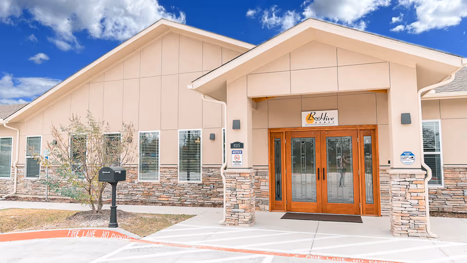 BeeHive Homes of Rowlett exterior entrance with wooden doors and stone accents.