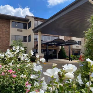 The entrance of Chapters Living of Joplin, featuring a covered awning and surrounded by colorful flowers.