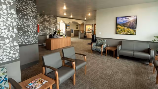 Reception and waiting area of a senior care facility with chairs, a front desk, and wall art.