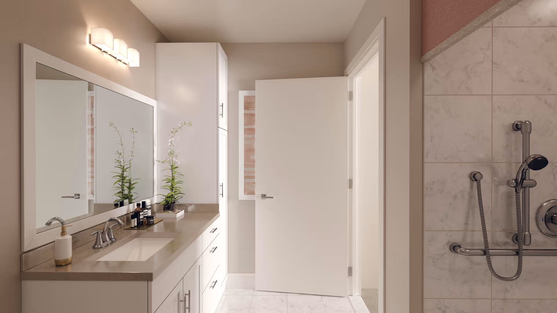 A modern bathroom with a large mirror above a beige countertop with a sink. There are two small plants and some toiletries on the counter. The bathroom features white cabinetry and a partially open white door. On the right side, there is a tiled shower area with a handheld showerhead and grab bars.