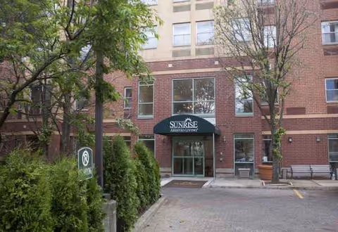 Brick exterior of Sunrise at Sheepshead Bay with glass doors and surrounding trees
