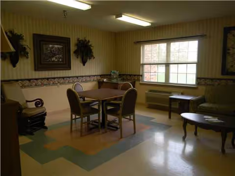 A shared living room with a square table, chairs, sofa, and a window.