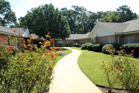 Curved concrete walkway winds through a manicured lawn to Meadowview Place exterior.