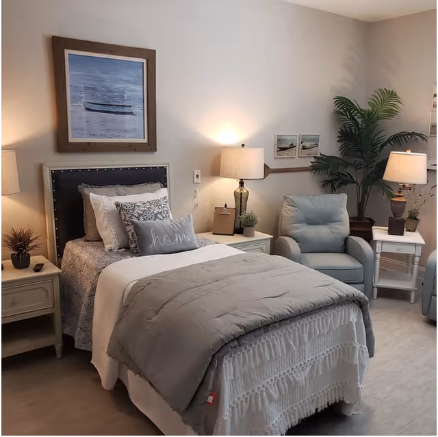 Cozy single-occupancy bedroom with a made bed, bedside tables and lamps, an armchair, and wall art.