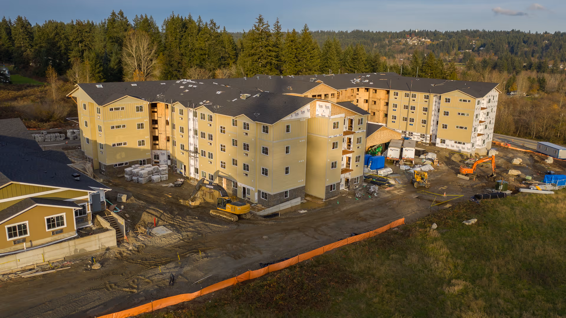 Aerial view of a multi-story senior living building complex under construction with construction equipment and materials on site.