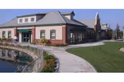 Exterior view of Sierra Village senior living facility with brick building, curved walkway, and pond.